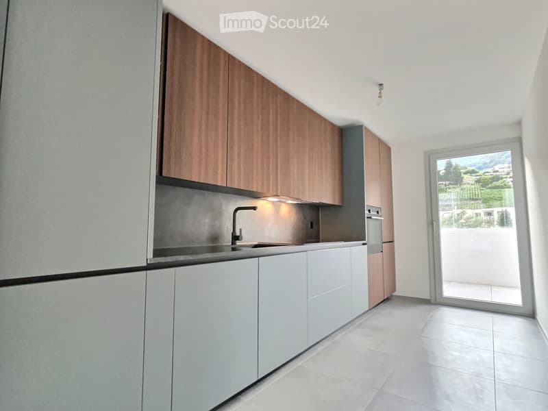Modern kitchen with white and wood cabinets, stainless steel sink, and built-in oven. Features a large window with a scenic view.