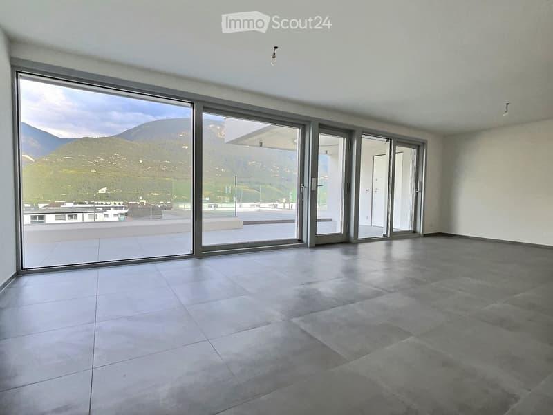 Empty room with large sliding glass doors leading to a balcony, tiled floor, and a scenic mountain view.