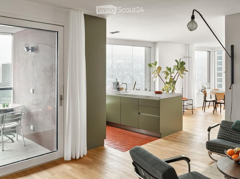 Modern, open-concept living and dining area with a kitchen island, sofa, dining table, and chairs. Large windows offer a city view, and the space includes a plant and a floor lamp.