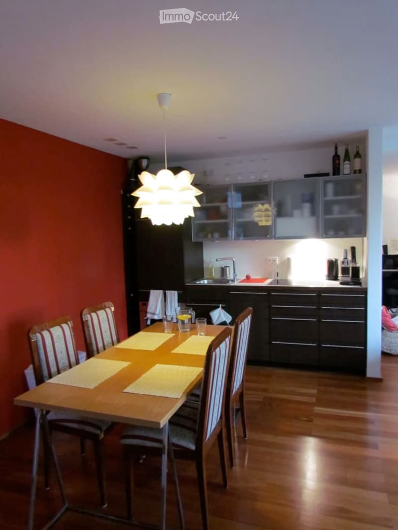 {"visible_features": [], "type": "Room", "description": "Dining room: wooden dining table, 6 chairs, wooden floor, ceiling lamp, red wall, modern kitchen with sink and faucet, wine bottles, wine glasses, cabinets and drawers.", "localized_descriptions": {