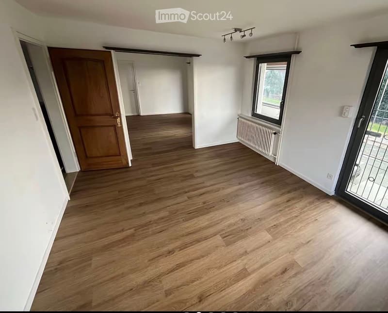 Empty room with wooden flooring, white walls, and large windows. No furniture or equipment present.