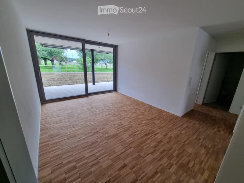 Empty room with wooden flooring and large sliding glass doors leading to an outdoor area.