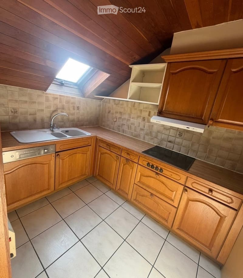 Bright kitchen with wooden cabinets, tiled floor, sink, dishwasher, and stove. Features a skylight window above the sink.