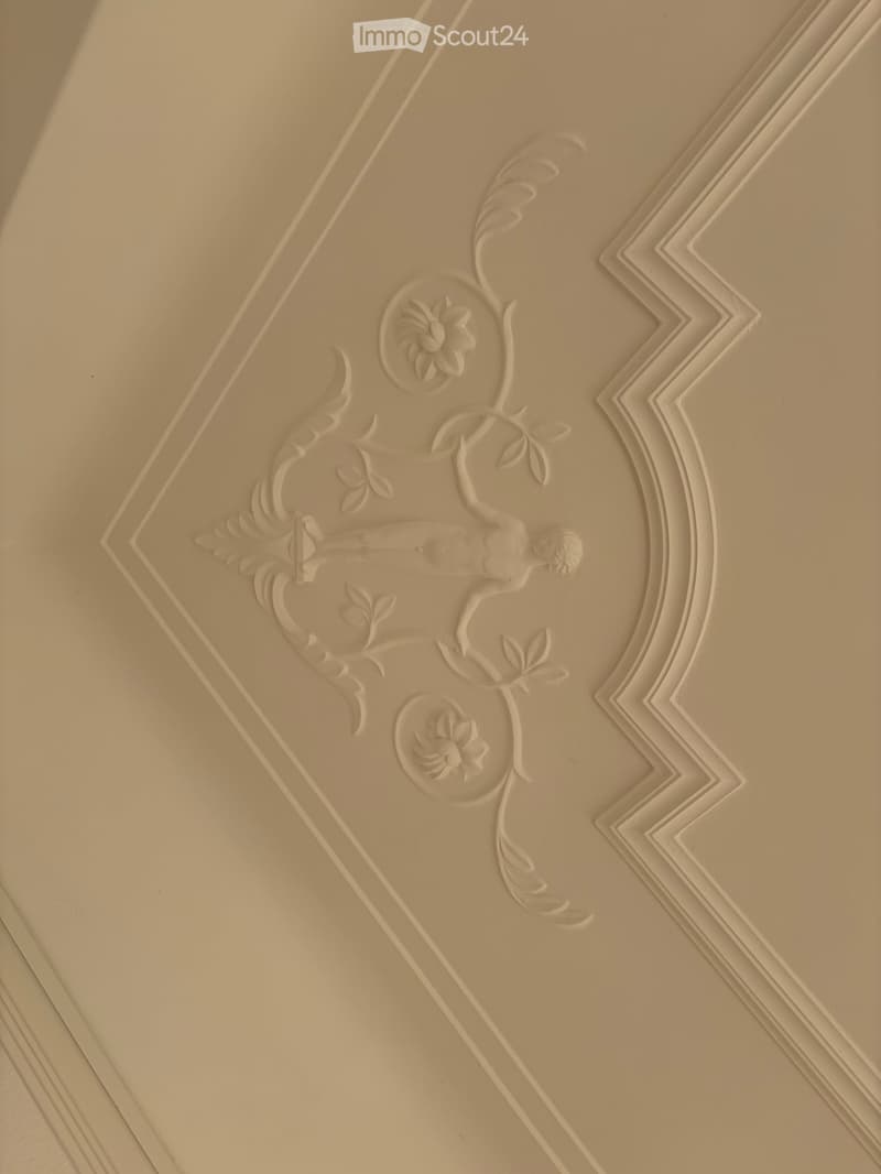Ornate ceiling with floral and leaf patterns, featuring a central decorative medallion and symmetrical design elements.