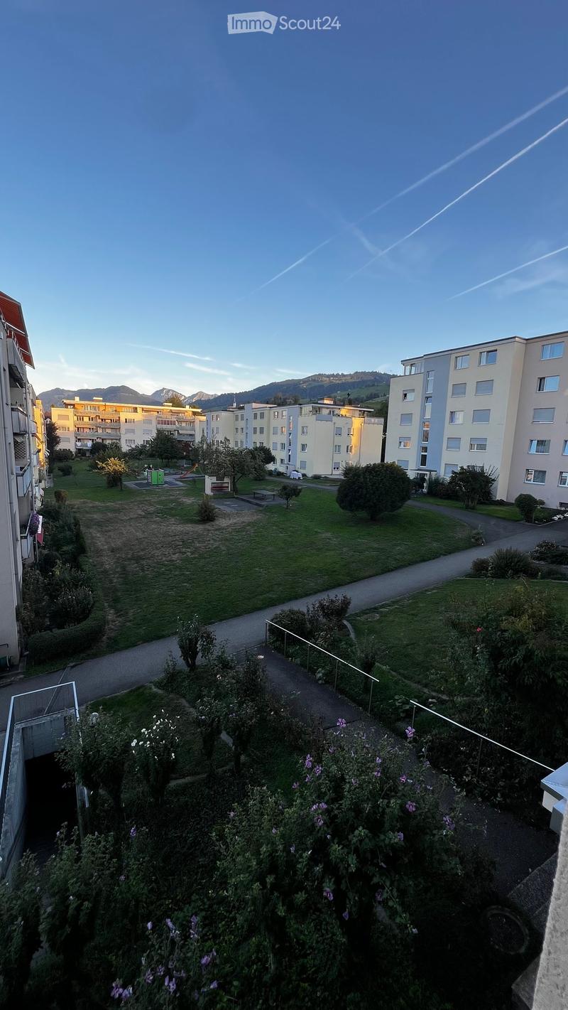 View of a residential area with green spaces, pathways, and buildings in the background.