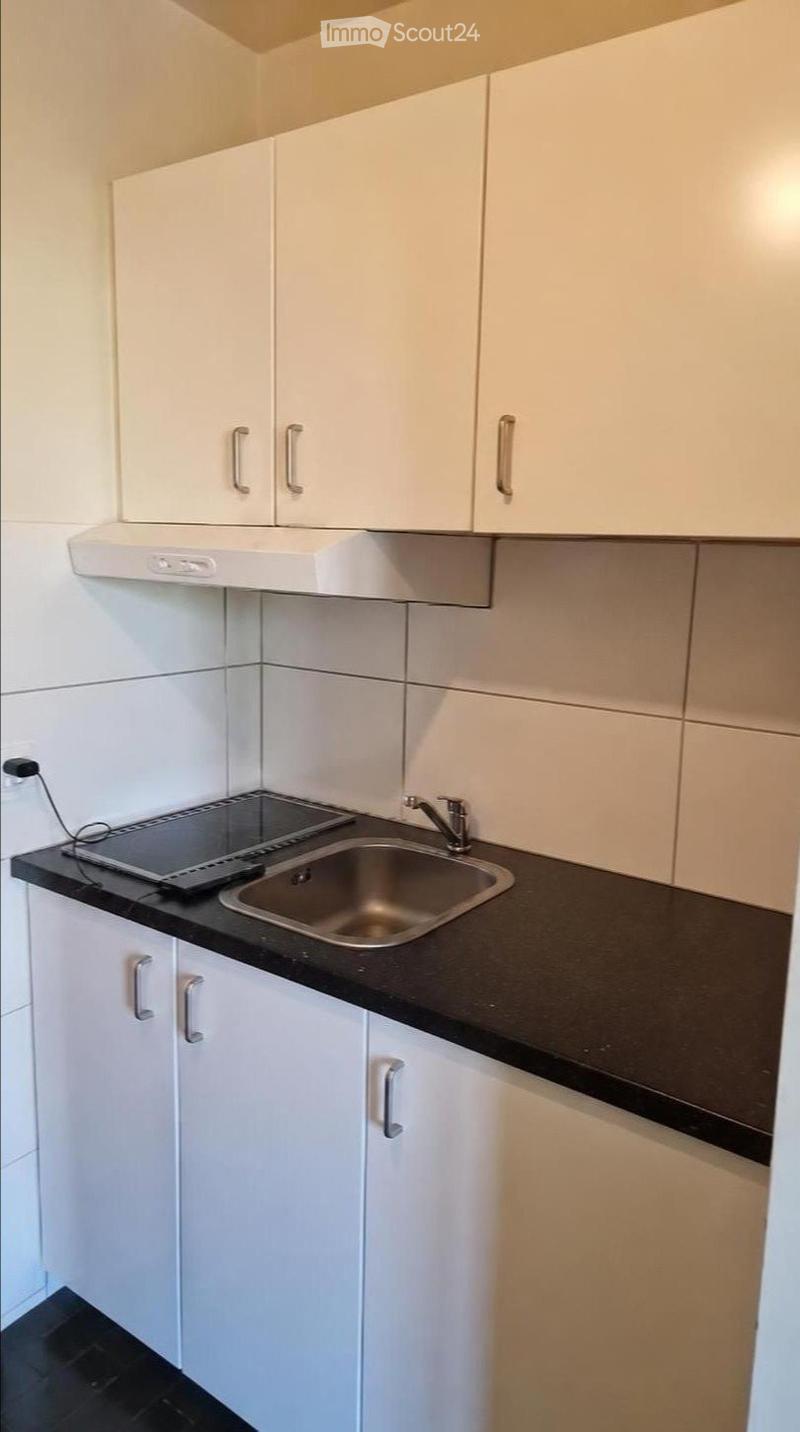 Modern kitchen with white cabinets, black countertop, stainless steel sink, and built-in stove.