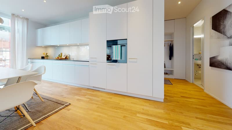 Modern kitchen and dining area with white cabinets, a round dining table with chairs, and a small plant on the counter.