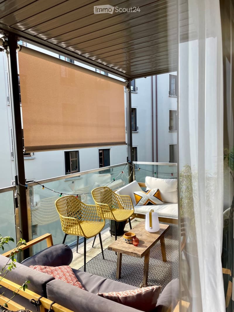 Balcony with a modern design, featuring a sofa, chairs, a coffee table, and decorative pillows.