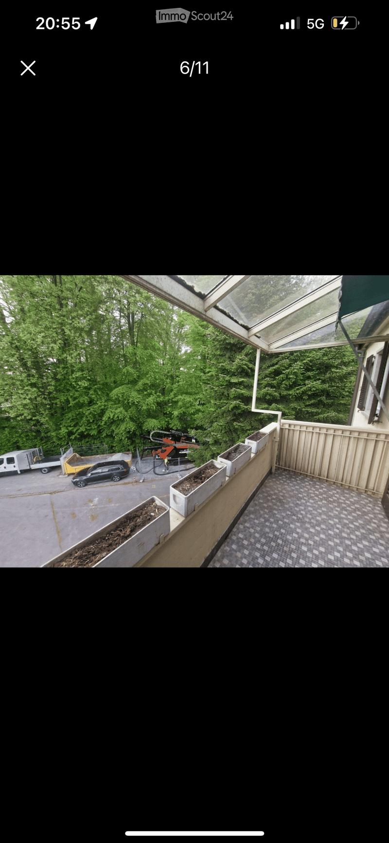 Balcony terrace with a view of a forested area, plants in containers, and paved floor