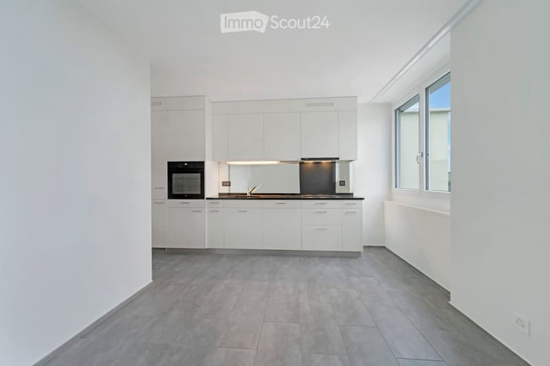 Modern kitchen with white cabinets, stainless steel appliances, and grey tiled flooring.