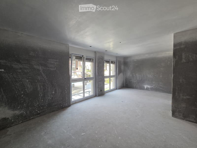 Empty room with bare concrete walls and floor, large windows, and no furniture or equipment.