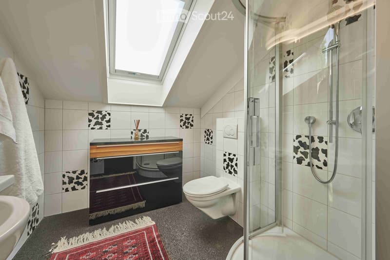 bathroom with a shower, toilet, sink, skylight, white tiles, red rug, hanging towels