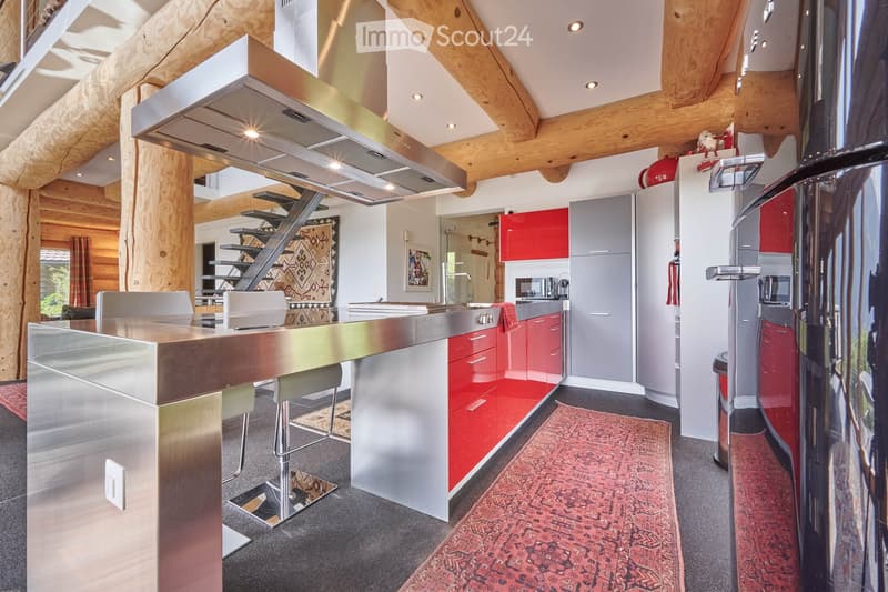 open kitchen, stainless steel countertops, red cabinets, refrigerator, microwave, stove, stainless steel hood, log ceiling, carpeted floor, trash can