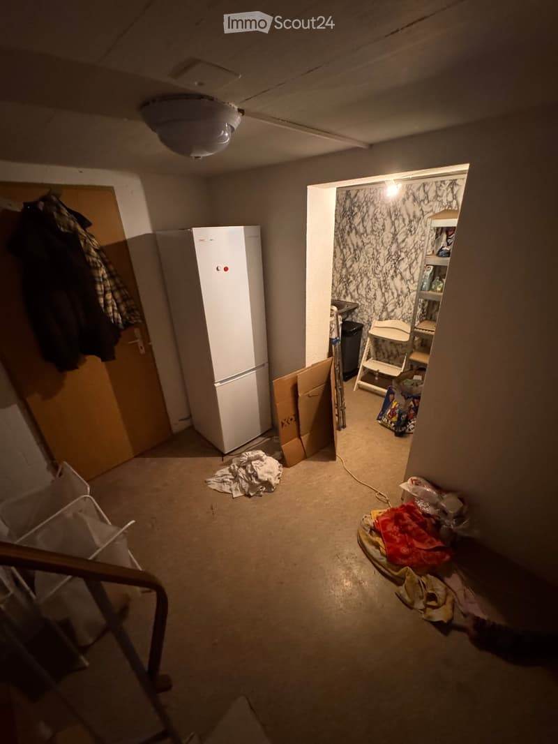 Empty room with a refrigerator, scattered items, and a partially open closet with shelves. The space appears to be in transition or storage.