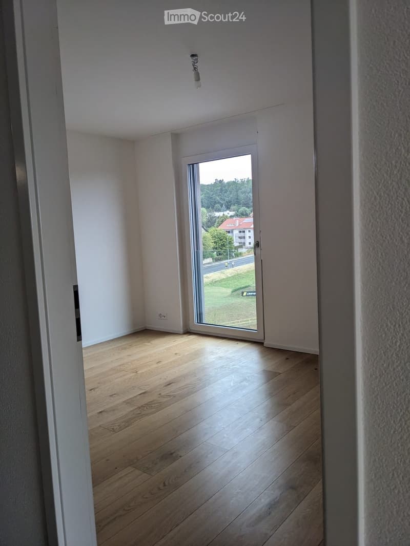 Empty room with wooden flooring, white walls, and a large sliding glass door leading to an outdoor view.