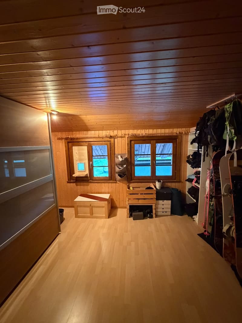 A wooden-paneled room with a bench, storage cabinet, skis, backpacks, and wooden crate.