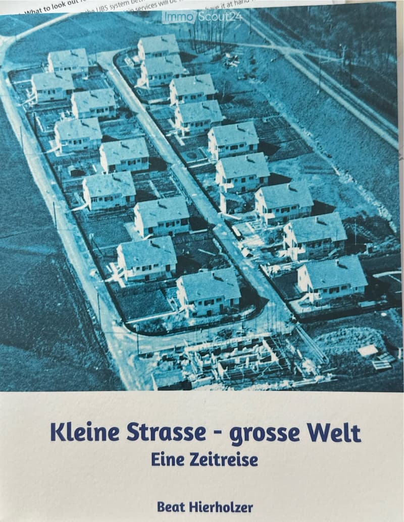 Aerial view of a residential area with multiple houses arranged in rows, surrounded by roads and pathways.