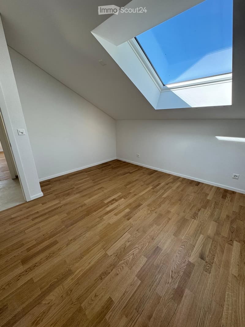 Empty room with wooden flooring, white walls, and a skylight window at the top.