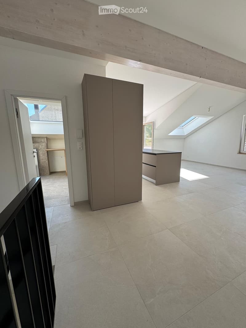 Empty room with tiled floor, white walls, and modern cabinetry. Features skylights and an open doorway leading to another room.
