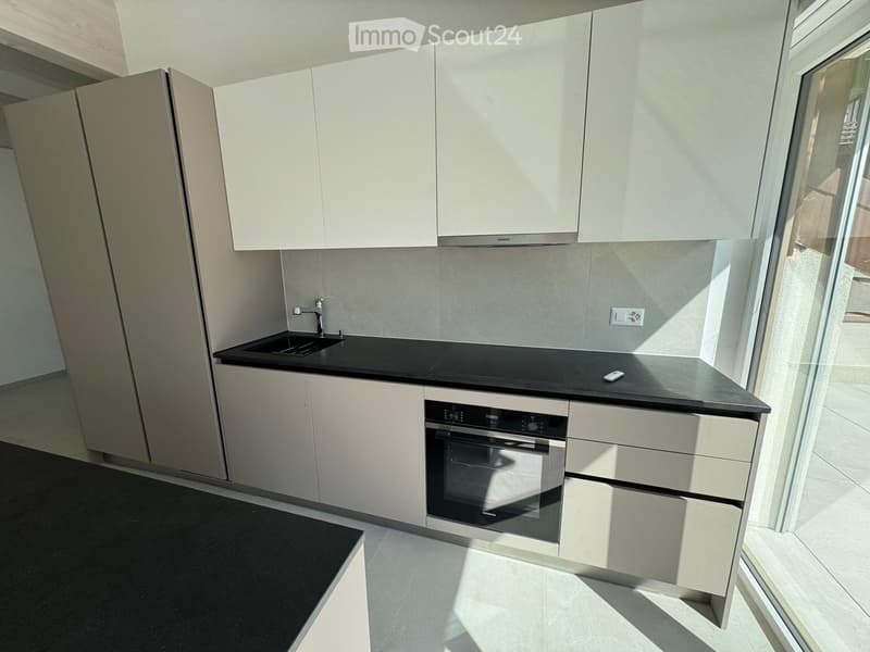 Modern kitchen with white cabinets, black countertops, and built-in oven. Features a sink with a modern faucet and ample storage space.