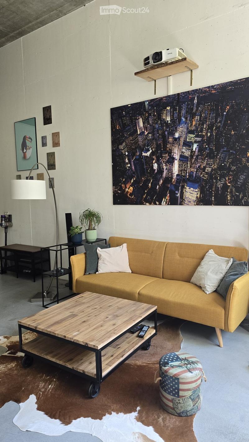 Modern living room with a mustard yellow sofa, wooden coffee table, floor lamp, and a large cityscape mural on the wall.