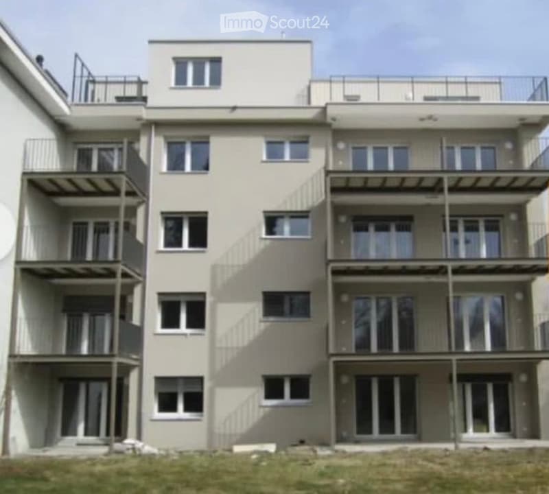 Modern multi-story residential building with multiple balconies and large windows.
