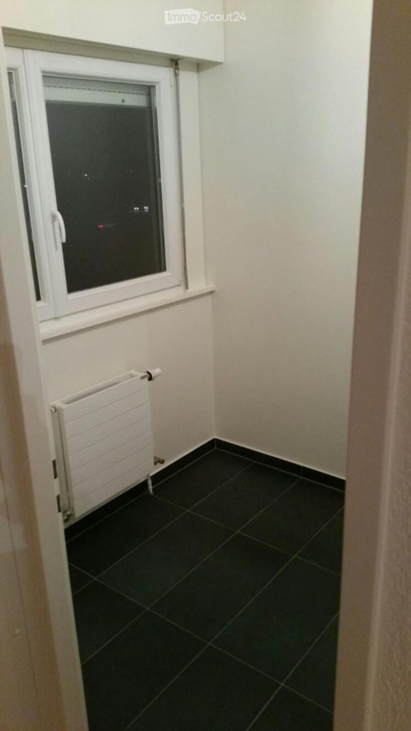 Empty room with black tiled floor, white radiator, and a window with white frame.