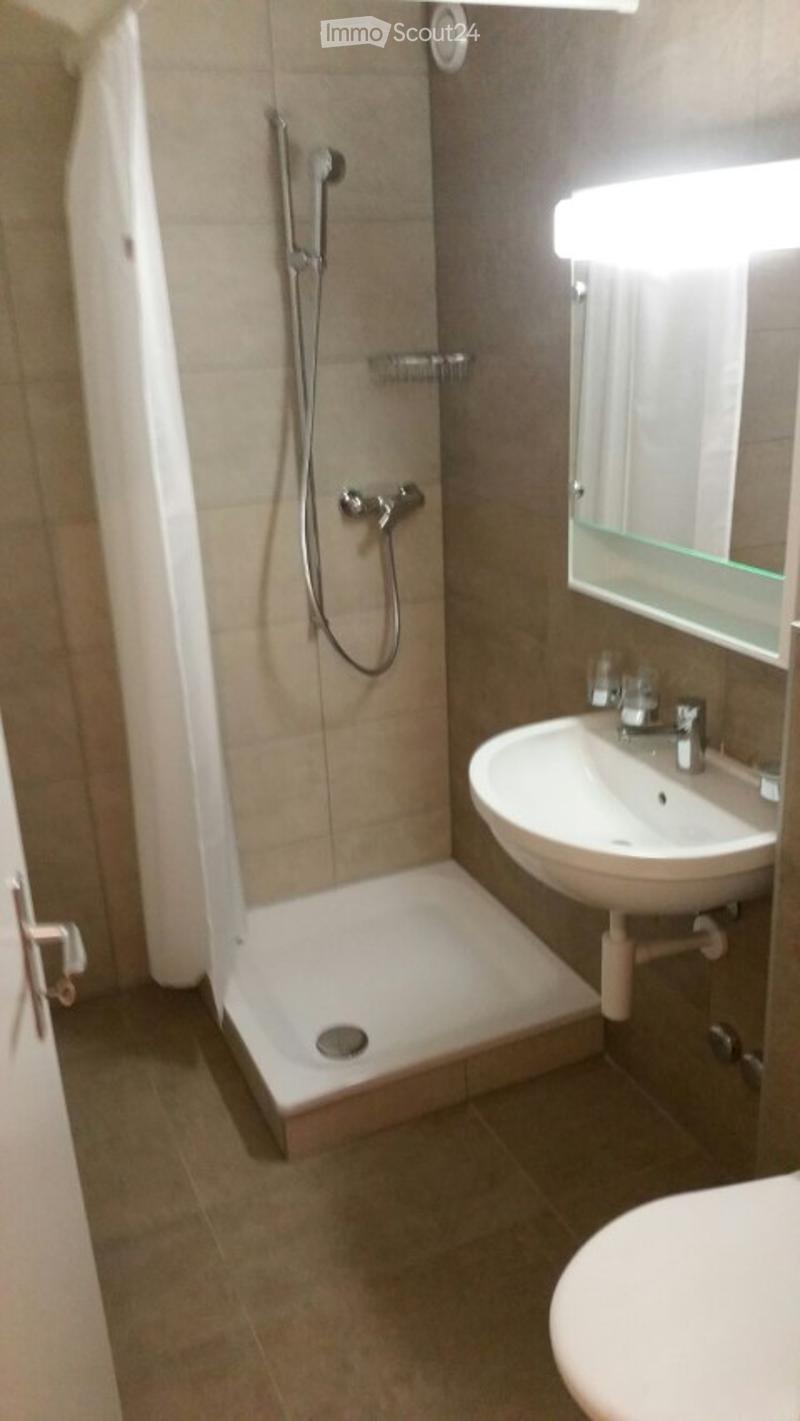 Modern bathroom with a shower, sink, and toilet. Features a glass shower enclosure, a modern mirror, and a sleek faucet.
