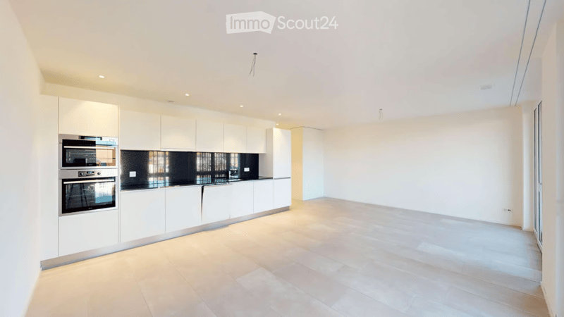 Modern kitchen with white cabinets, stainless steel oven, and light wooden flooring.