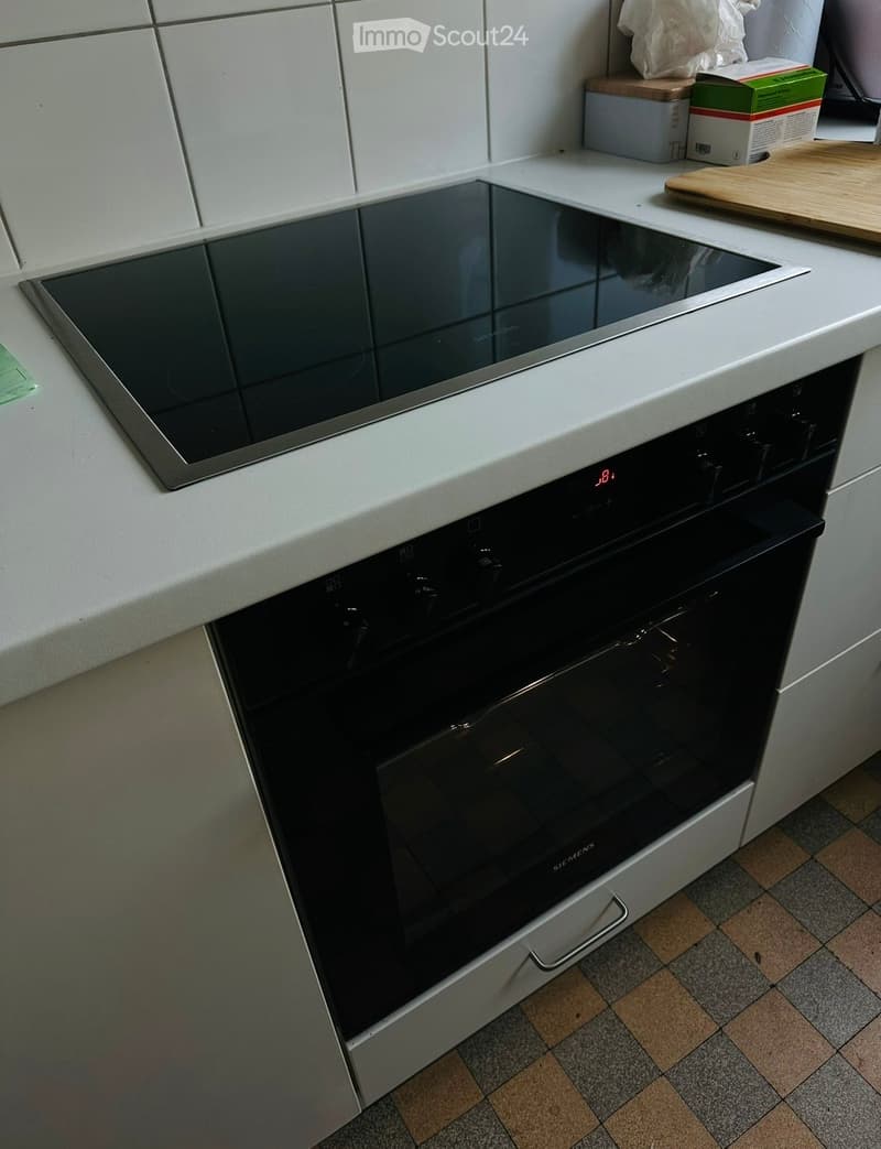 Modern kitchen with an induction stove and built-in oven, white cabinets, and a tiled floor.