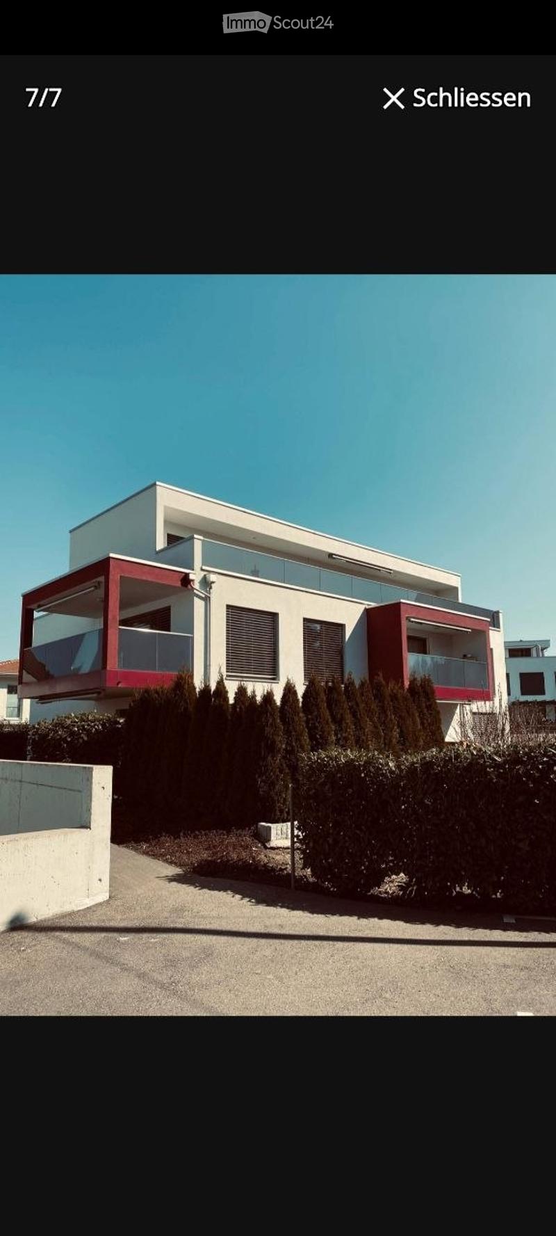Modern two-story house with white and red exterior, large windows, and balconies.