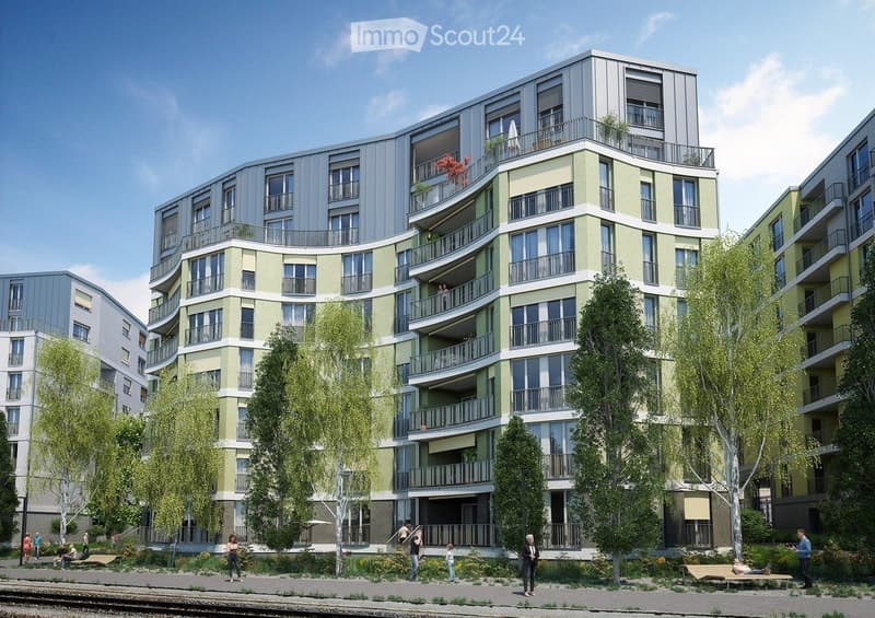 Modern multi-story residential building with balconies, green facade, and surrounding greenery. People are seen walking and sitting on benches in the foreground.