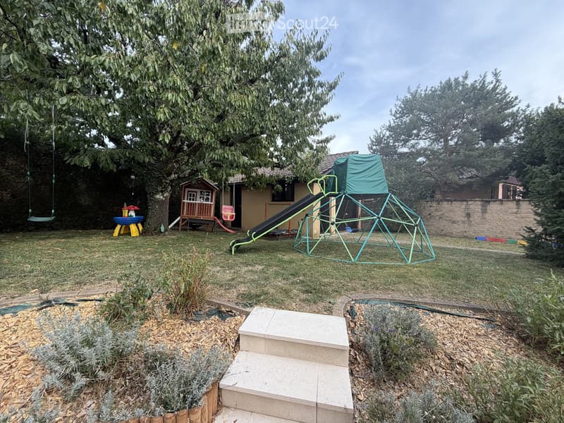 Backyard with a swing, small playhouse, slide, climbing frame, and steps leading up to the house.