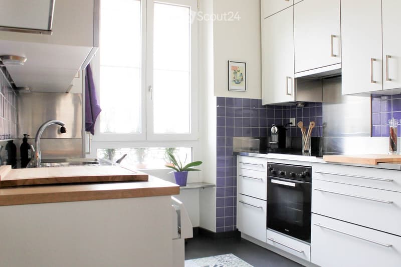 Modern kitchen with white cabinets, stainless steel appliances, and a wooden countertop. Features include a sink with a modern faucet, an oven, and a coffee maker on the counter.