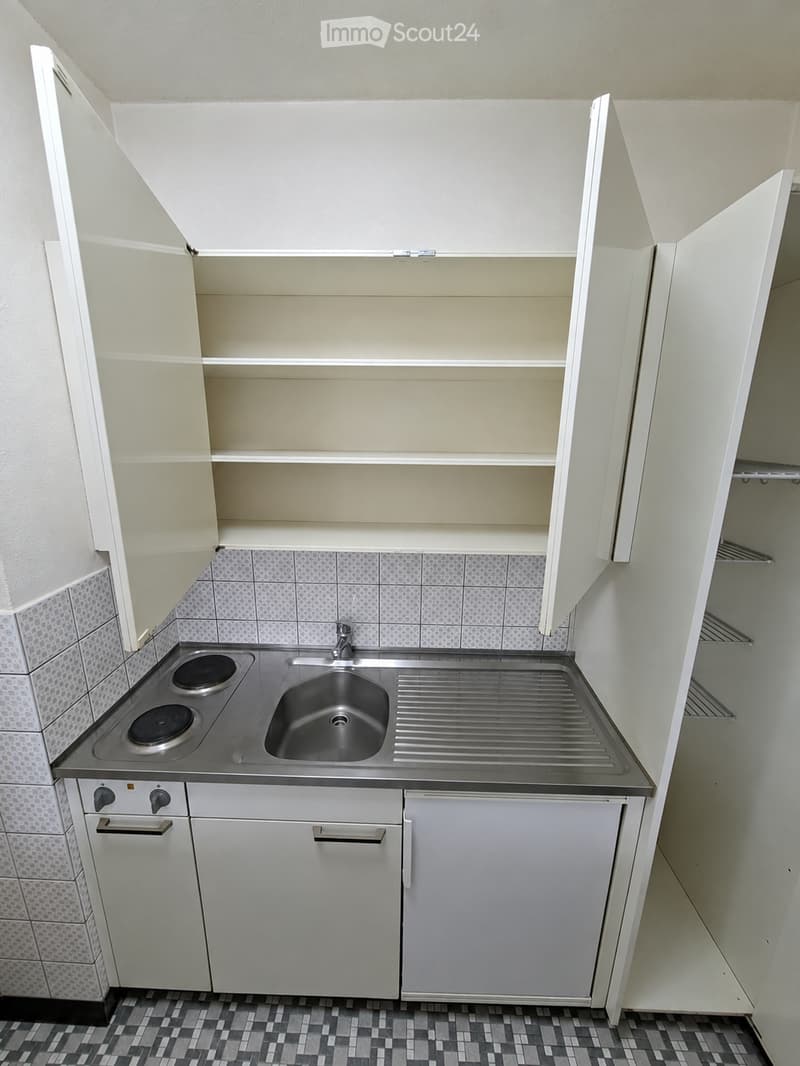 Compact kitchen with white cabinets, a sink, an induction cooktop, and tiled walls and floor.