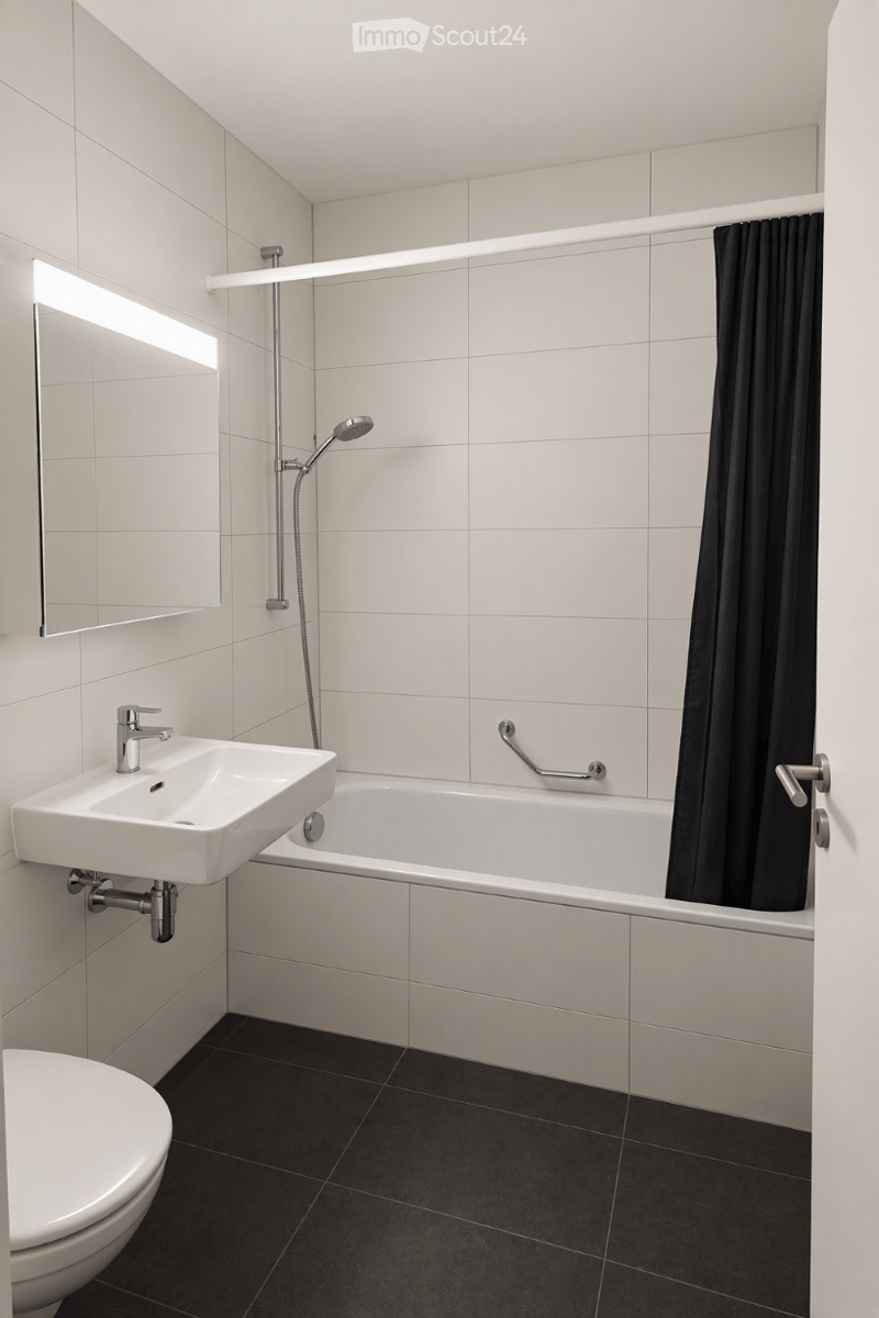 Modern bathroom with white tiles, a bathtub, a sink, a toilet, a mirror, and a showerhead with a black curtain.