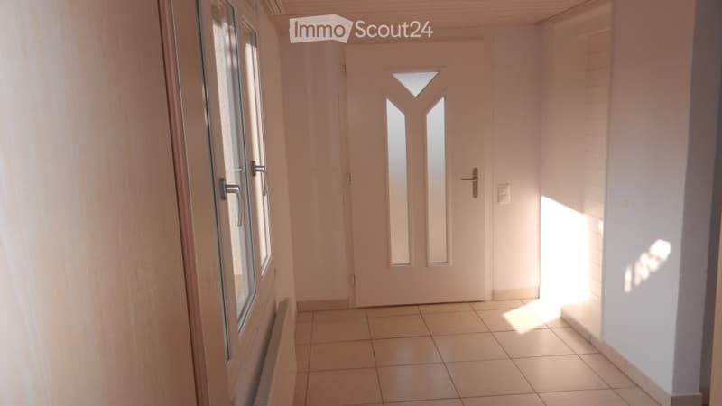 Empty hallway with white walls, tiled floor, white door, glass windows, power outlet