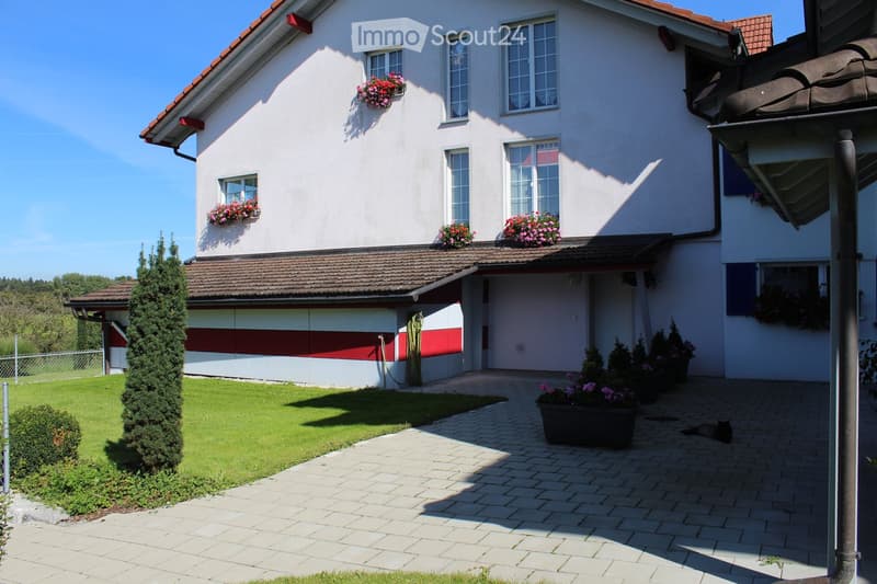 2 story house, white exterior, red roof, red and white garage, flower boxes, brick driveway