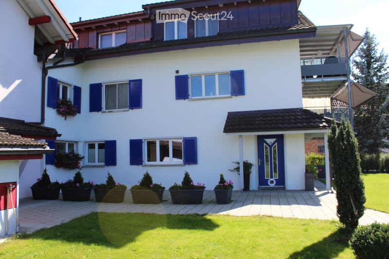 2 story house, white exterior, blue shutters, blue door, balcony, well-maintained garden, multiple potted plants