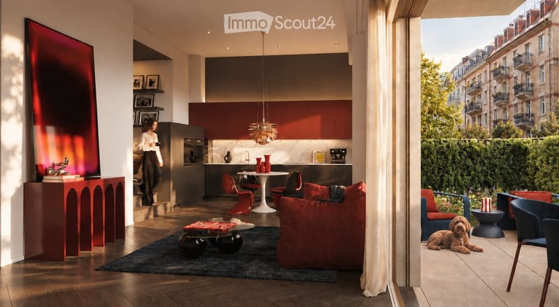 Modern living room with a sofa, coffee table, chairs, a kitchen area with cabinets and a kitchen island, pendant light, large screen, vases, and picture frames. The room has wooden flooring and large windows with a view of the city.