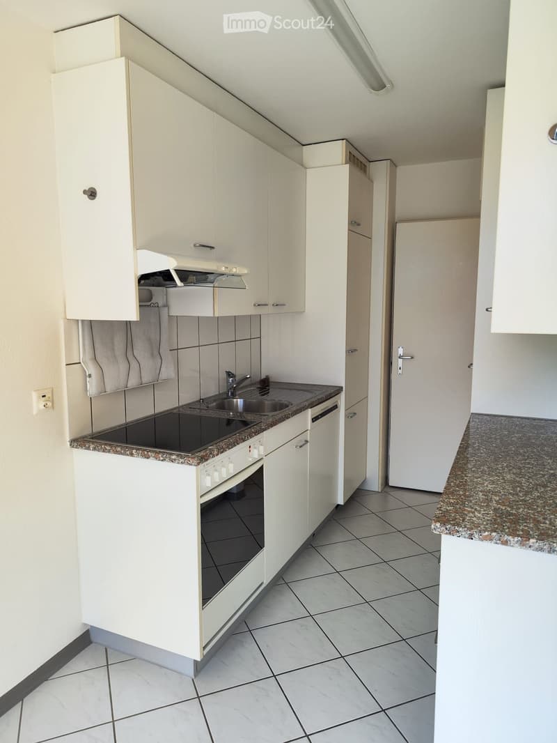 Modern kitchen with white cabinets, granite countertops, tiled floor, and stainless steel appliances including a sink, oven, and dishwasher.