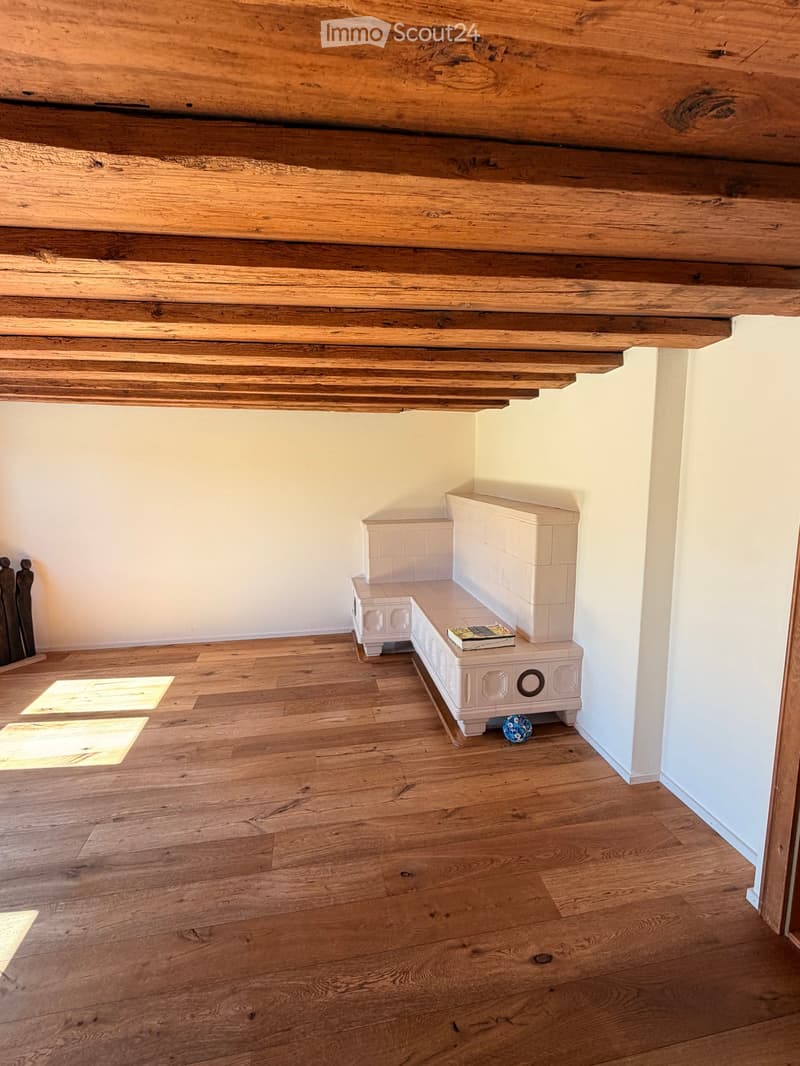 Wooden floor and exposed wooden ceiling with a white bench and a book on top.