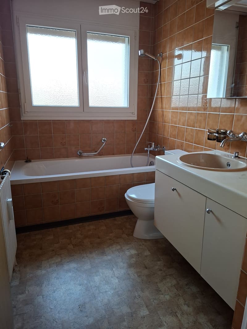 bathroom with bathtub, white toilet, sink, brown tiles, white cabinetry, radiator