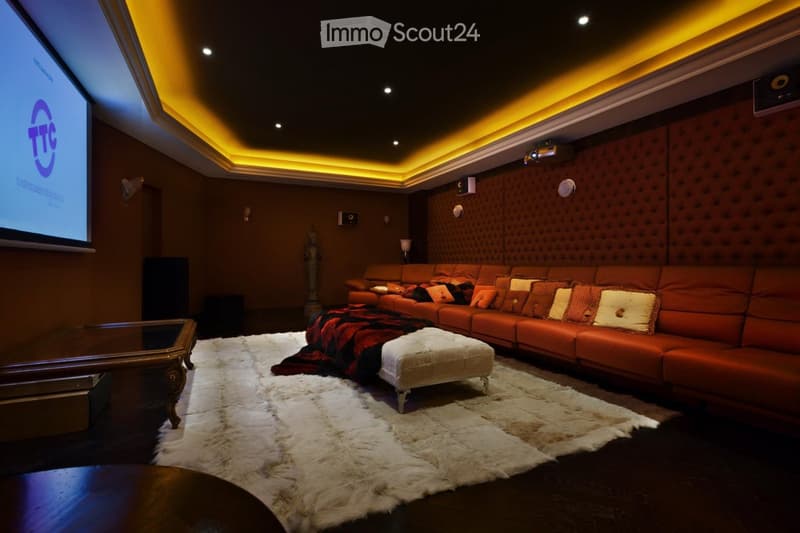 Theater room with a large sectional sofa, ottoman, coffee table, and a large screen for viewing.