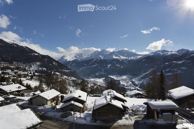 A picturesque village nestled in a snow-covered valley with traditional wooden houses and a backdrop of snow-capped mountains.