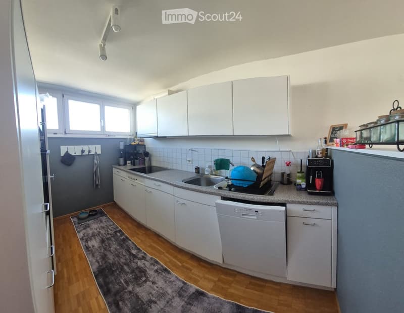 Modern kitchen with white cabinets, granite countertop, stainless steel appliances, and wooden flooring.