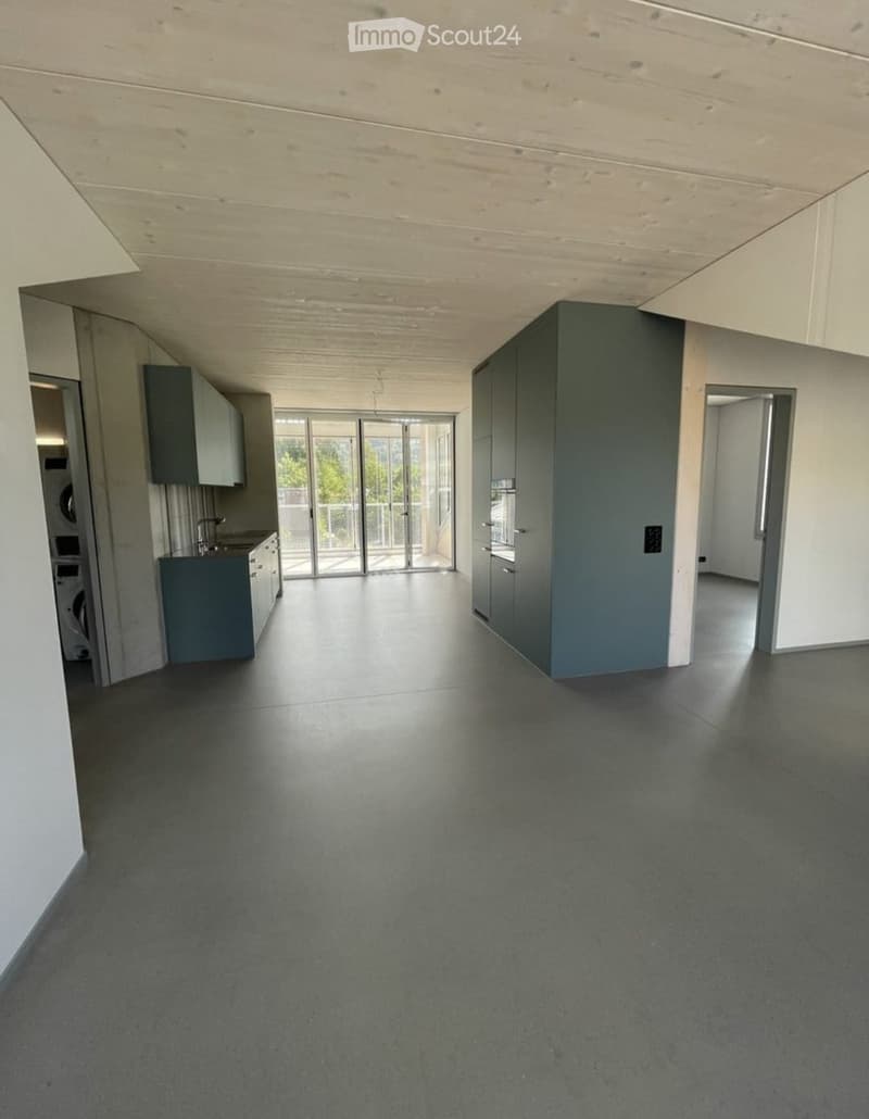 Empty room with grey cabinets, a washing machine, and a sliding glass door leading to a balcony.
