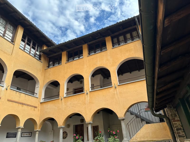 A multi-story yellow building with arched windows and balconies, featuring a staircase leading to an upper level.