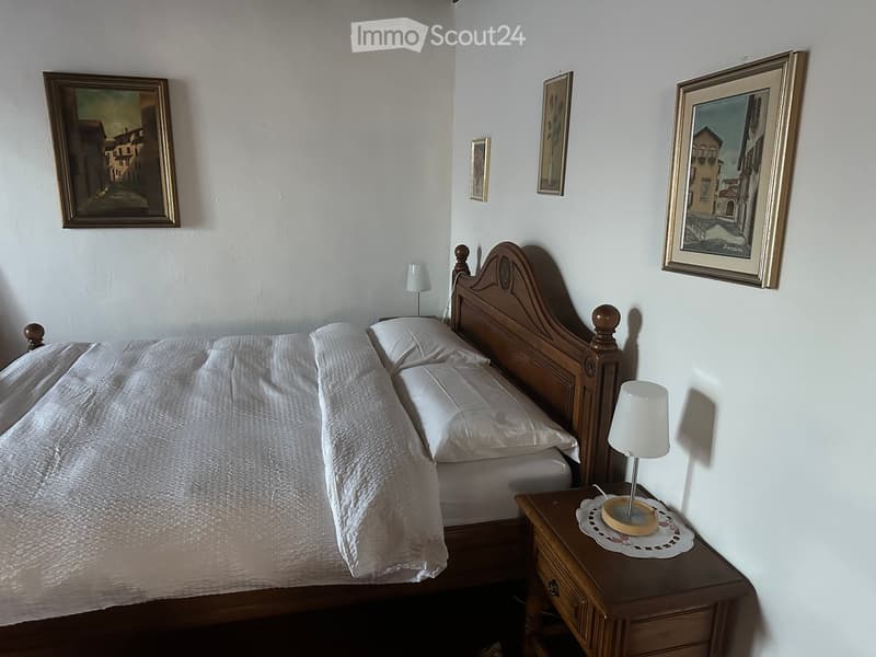 Cozy bedroom with a wooden bed, nightstand, lamp, and framed artwork on the walls.