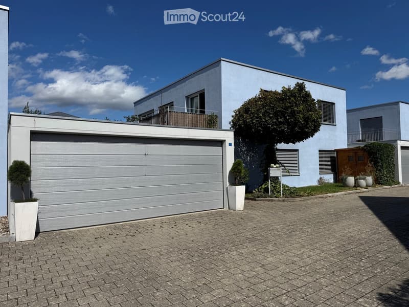 Modern two-story house with a garage, balcony, and well-maintained garden area.